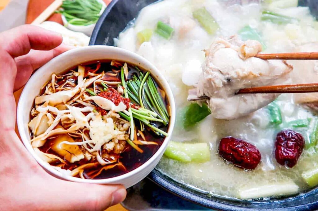Hands mixing soy sauce, mustard, and minced garlic into a personal dipping sauce bowl at Hongdae Dak Hanmari