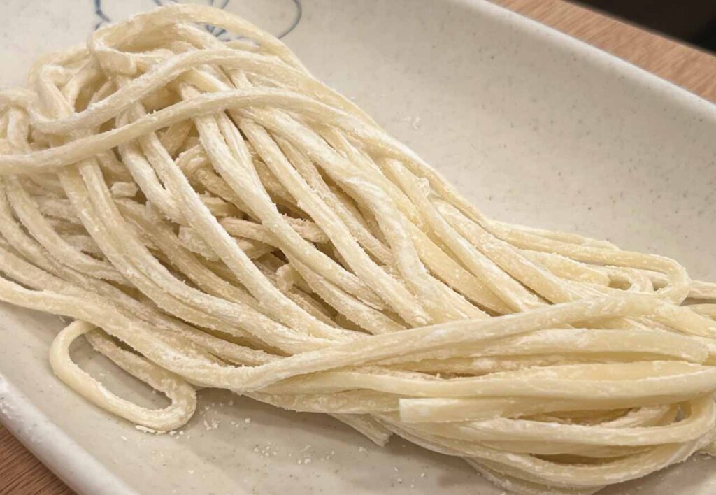 Kalguksu hand-cut noodles being added into the rich golden chicken broth at Hongdae Dak Hanmari for the final course